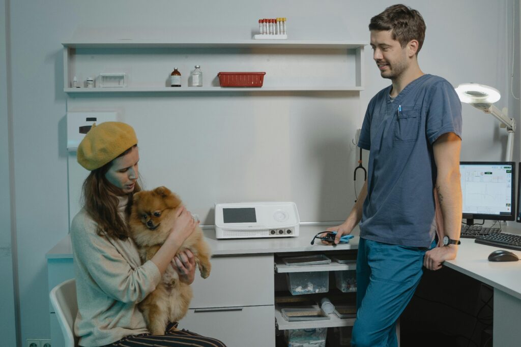 A veterinarian in a clinic consulting with a pet owner and her Pomeranian dog.
